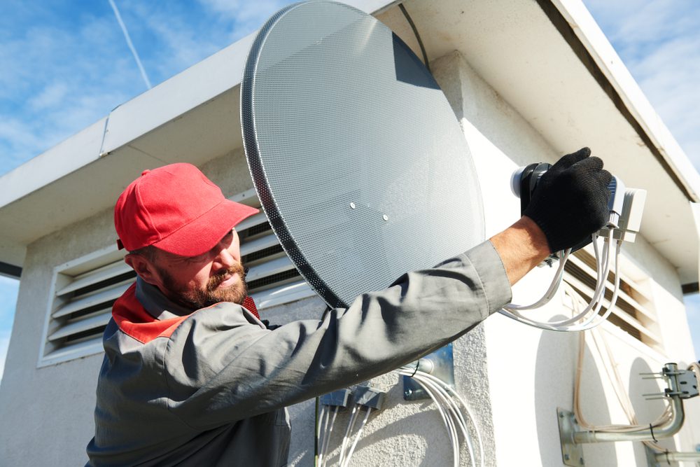 Electrician installing antenna on wall
